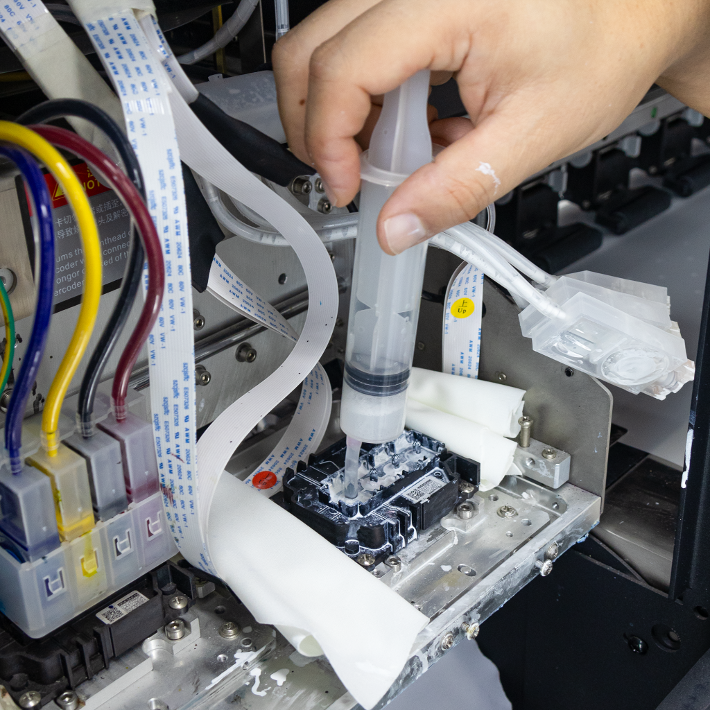 Technician replacing DTF printer ink with parts laid out